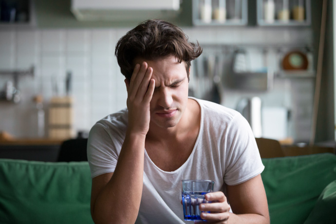 Hombre con dolor de cabeza porque le siente mal el alcohol.