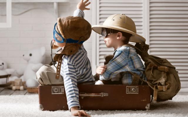 Niños jugando a viajar en avión dentro de una maleta