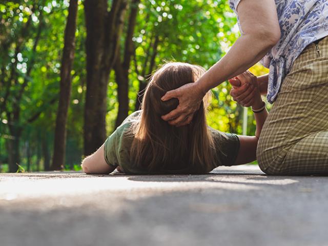 Mujer en el suelo siendo asistida por otra persona.