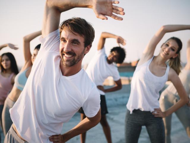 Grupo de personas jóvenes y deportistas haciendo estiramientos al aire libre