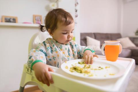 Niña pequeña comiendo en su silla alta